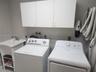 Utility room featuring white cabinetry, a freestanding basin with a chrome faucet, and integrated laundry hookups