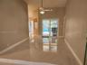 High-ceiling living area featuring large-format polished porcelain tile flooring, sliding glass doors, and a ceiling fan