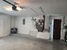 Garage featuring concrete flooring, an overhead automatic door opener, a dedicated HVAC unit, an electrical panel, and an access door