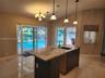 Kitchen featuring an island with a stone countertop, dark wood-finish cabinetry, an undermount sink, a gooseneck faucet, and three pendant light fixtu