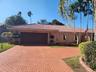 Stucco exterior featuring a clay tile roof, arched covered entry, paver driveway, and mature landscaping