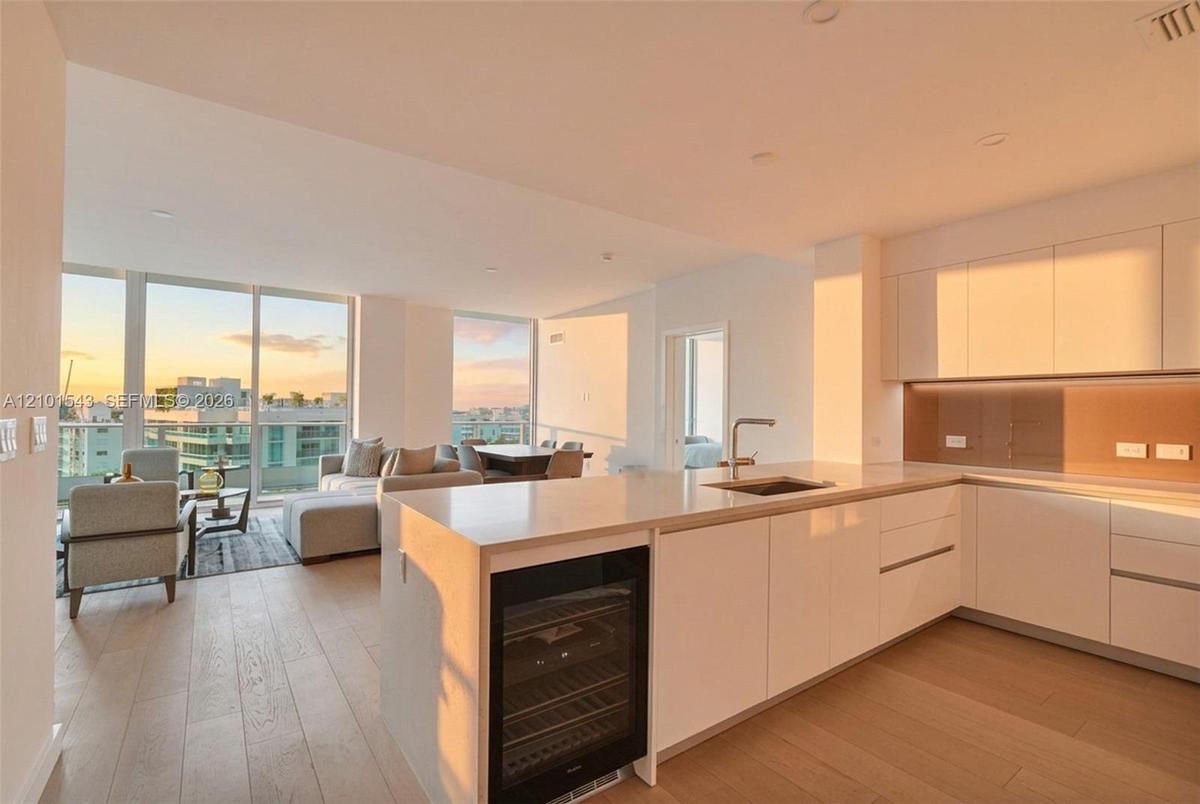Kitchen featuring high-gloss cabinetry, stone countertops, integrated wine refrigeration, wood-finish flooring, and floor-to-ceiling windows