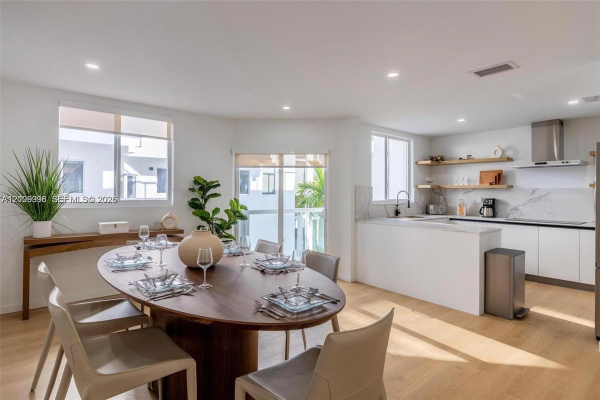 Kitchen featuring white cabinetry, quartz-surface countertops, stone-patterned backsplash, and natural wood-finish open shelving