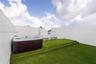 Rooftop terrace featuring synthetic grass surfacing, tiered platform levels, high perimeter walls for privacy, and a built-in spa