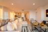 Open-concept living space featuring wood-finish flooring, recessed lighting, and a kitchen equipped with a stone-top island, built-in cabinetry, and m