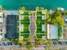 Aerial perspective featuring direct waterfront access, paved central driveway, rooftop artificial turf terraces, and established tropical vegetation