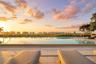 Infinity-edge swimming pool featuring stone tile decking, metal entry handrails, and a horizon backdrop