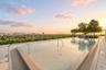 Rooftop swimming pool featuring a tiled deck, metallic handrails, and surrounding mature landscaping