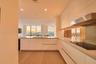 Contemporary kitchen featuring flat-panel cabinetry, light-toned wood-finish flooring, a stainless steel range hood, an integrated cooktop, and floor-