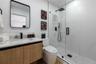 Floating wood-finish vanity with a composite countertop and integrated basin, matte black wall-mounted faucet, rectangular mirror with rounded corners