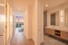Floating wood-finish vanity with dual sinks, stone flooring, walk-in tile shower with glass enclosure, recessed lighting, and wall-mounted vanity mirr