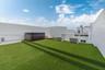Rooftop terrace featuring tiered synthetic turf flooring, built-in hot tub, and glass perimeter railings