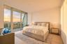 Floor-to-ceiling glass wall with access to an exterior balcony, light-toned wood-finish flooring, and recessed ceiling lighting