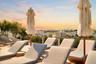 Rooftop terrace featuring light-toned tile flooring, lush perimeter landscaping, and a panoramic skyline backdrop