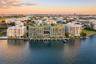 Waterfront mid-rise building featuring boat slips, a rooftop terrace with landscaping, floor-to-ceiling glass windows, and a central courtyard