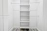 Walk-in closet featuring white built-in shelving, dual-level garment rods, and wood-finish flooring