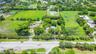 Aerial perspective of expansive acreage featuring mature trees, manicured landscaping, a circular driveway, and a gated entrance