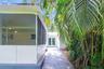 Screened lanai featuring a concrete patio, dual glass-panel entry doors, and mature palm trees