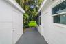 Stucco exterior walls, gray painted concrete pathway, screen-enclosed area, and mature landscape