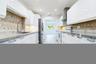 High-gloss white cabinetry, stone countertops, diamond-pattern tile backsplash, stainless steel appliances, and recessed lighting