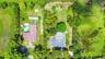 Aerial perspective of a sprawling property featuring two distinct residential structures, a swimming pool, mature perimeter landscaping, and expansive
