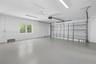 Multi-car garage featuring a smooth-finish floor, white walls, dual overhead fluorescent lighting, and an automatic sectional door