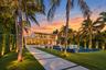 Modern architectural exterior featuring floor-to-ceiling glass wall systems, a second-story balcony with metal railings, a tiled infinity-edge pool, a
