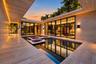 Central courtyard featuring a reflecting pool with integrated planters, floor-to-ceiling glass panel walls, natural stone-finish decking, and recessed