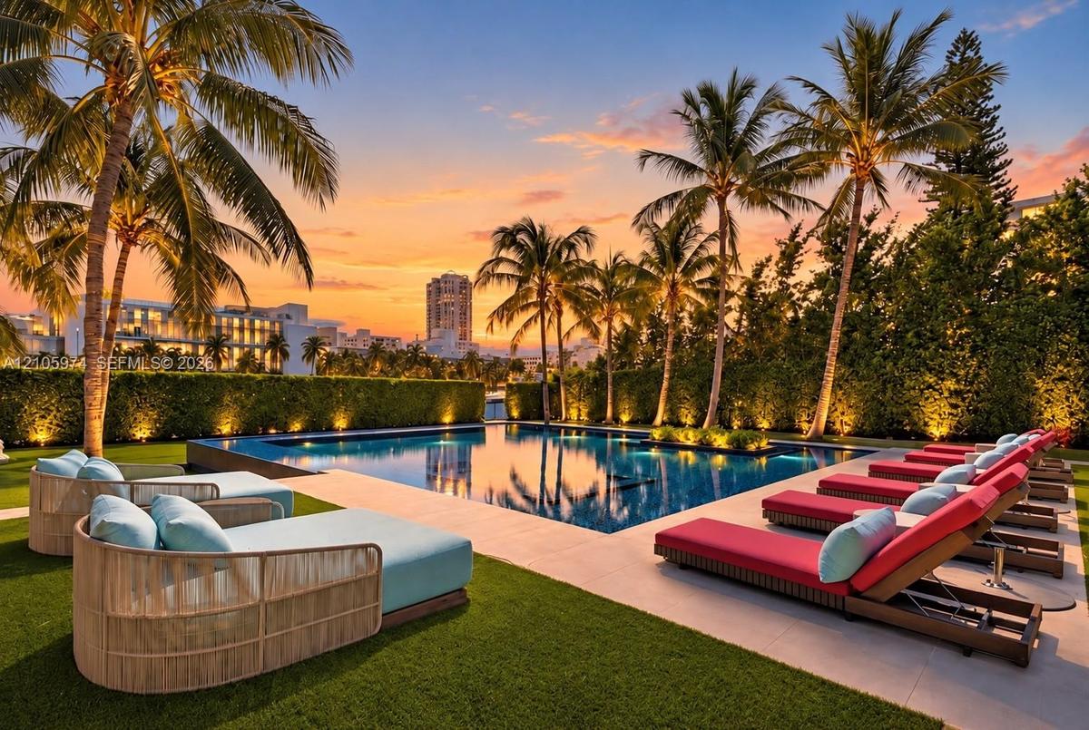 Swimming pool with stone-surround decking, manicured lawn, and mature palm trees