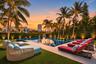 Swimming pool with stone-surround decking, manicured lawn, and mature palm trees