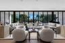 Floor-to-ceiling retractable glass walls, wide-plank wood-finish flooring, recessed ceiling lighting, and expansive stone-clad wall accents