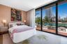 Floor-to-ceiling glass sliding doors, private balcony with wood-finish decking, glass railing, and neutral wall textures