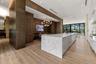 Large kitchen featuring a waterfall-edge stone island, wood-panel wall treatments, wood-finish flooring, a multi-globe chandelier, and expansive slidi