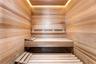 Sauna interior featuring natural wood wall paneling, tiered slatted benches, and recessed perimeter ceiling lighting