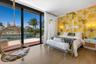 Floor-to-ceiling sliding glass walls, expansive terrace with wood-finish decking, glass-panel railing, and wood-finish flooring