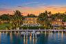 Waterfront estate featuring a deep-water dock, multi-level exterior architecture with floor-to-ceiling glass, an expansive swimming pool, and manicure