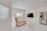 Open-concept area featuring white tile flooring, recessed ceiling lighting, plantation shutters, and a built-in stainless steel refrigerator with over