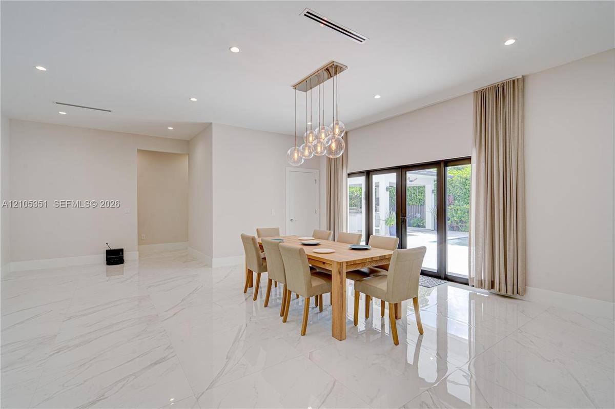 Open-concept space featuring polished stone-finish flooring, high ceilings with recessed lighting, multi-pendant spherical chandelier, and full-height