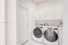 Laundry area featuring white cabinetry, solid-surface flooring, and neutral wall tones