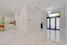 Large-format polished tile flooring, glass-panel front door with transom window, high-gloss white cabinetry, integrated wall oven, and tiered crystal 