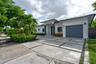 Contemporary single-story exterior featuring white stucco siding, a charcoal-toned garage door, geometric concrete paver driveway with decorative ston