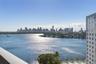 Elevated balcony with a metallic railing overlooking an expansive waterway and a prominent urban skyline