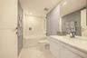 Bathroom featuring a white vanity with an integrated sink, a large wall-mounted mirror, a tub-shower combination with a glass panel, and polished tile