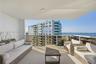 Covered balcony featuring a concrete floor, glass panel railing, and ceiling-mounted lighting