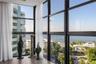 Floor-to-ceiling black metal-framed windows, wood-finish flooring, and coastal scenery
