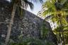 Natural stone masonry wall featuring custom metal signage, accented by mature palm trees and tropical landscaping