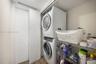 Laundry closet featuring a stacked washer and dryer unit, flat-panel door, and wood-finish flooring