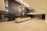 Lobby featuring high-gloss flooring with inlaid curvilinear detailing, a dark-finish wood-paneled accent wall with metallic leaf-shaped wall art, a st