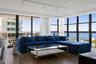 Floor-to-ceiling windows with black metal frames, wood-finish flooring, ceiling-mounted track lighting, and a sliding glass door opening to a private 