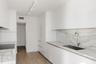 Modern kitchen featuring white flat-panel cabinetry, stone-finish countertops and backsplash, integrated refrigerator, undermount sink with high-arc f